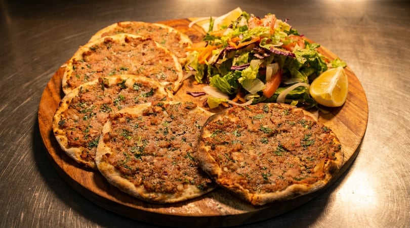 Lahmacun, Turkish flatbreads topped with minced meat and herbs, served with a fresh salad and lemon.